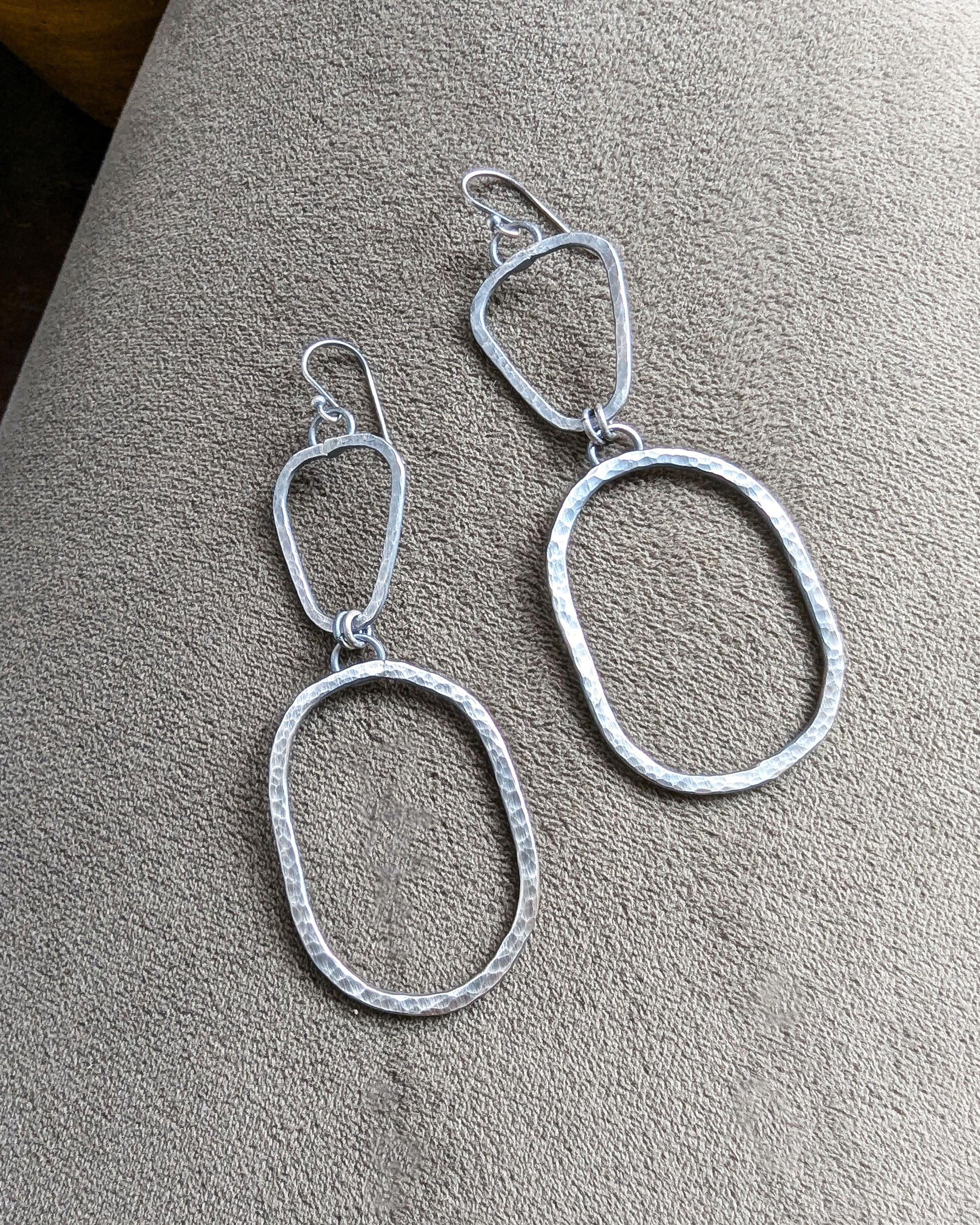 Silver earrings on a textured grey surface .