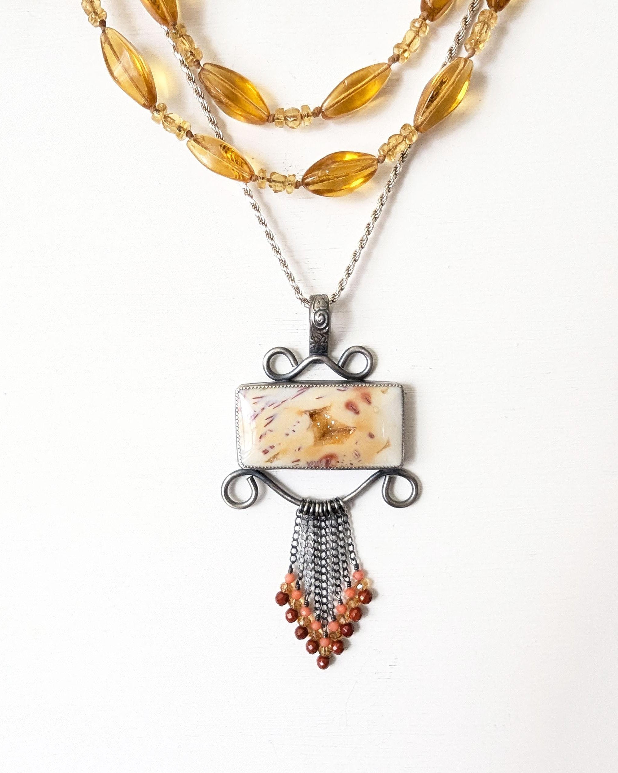 Rectangular agate statement pendant with coral and jasper fringe shown on chain with layering necklaces for styling