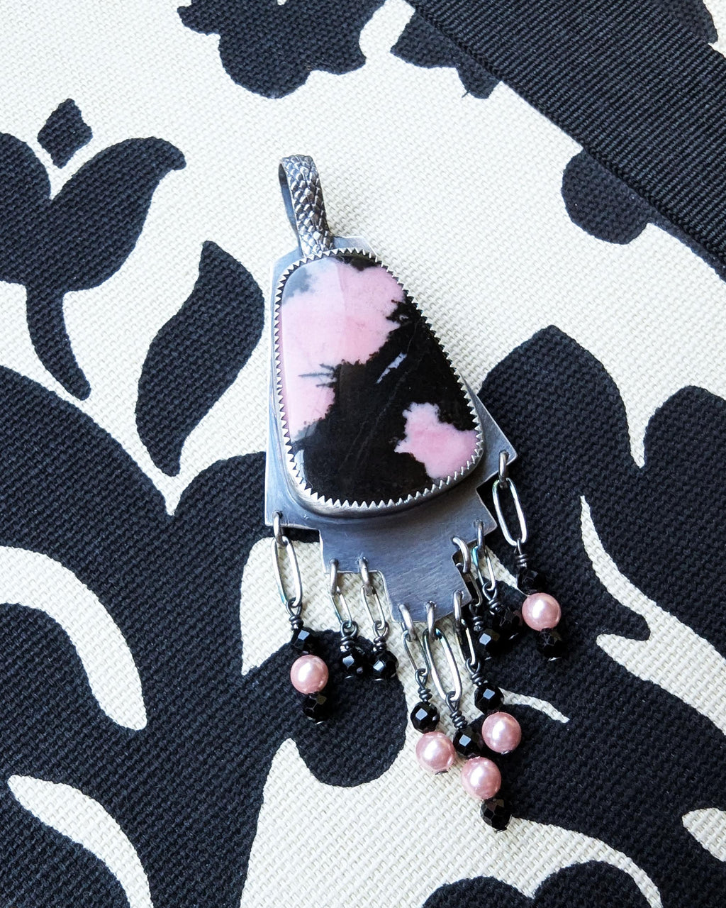 Hand-cut oxidized silver step design with symbolic pink stone