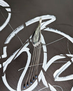 Leaf shaped pendant with hanging beaded fringe on a dark abstract background