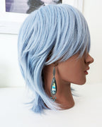 Mannequin head with light blue hair on a white background with silver and multi colored drop earring