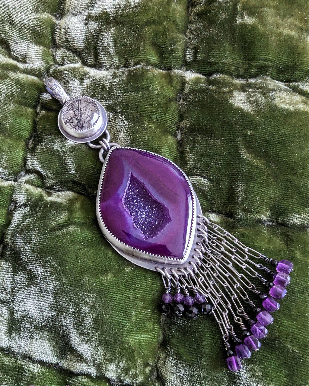 Close up of a regal two-stone pendant featuring druzy agate and black tourmaline with amethyst accents
