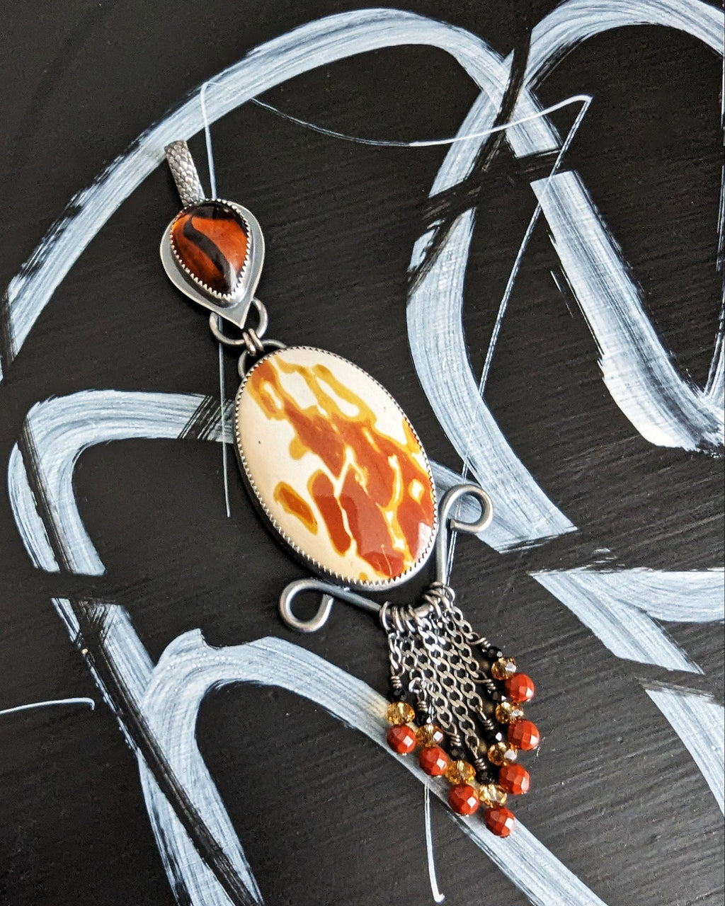 Jewelry pendant with flame-like design on a black and white abstract background