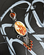 Jewelry pendant with flame-like design on a black and white abstract background