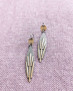 Geometric earrings on a light purple textured fabric background