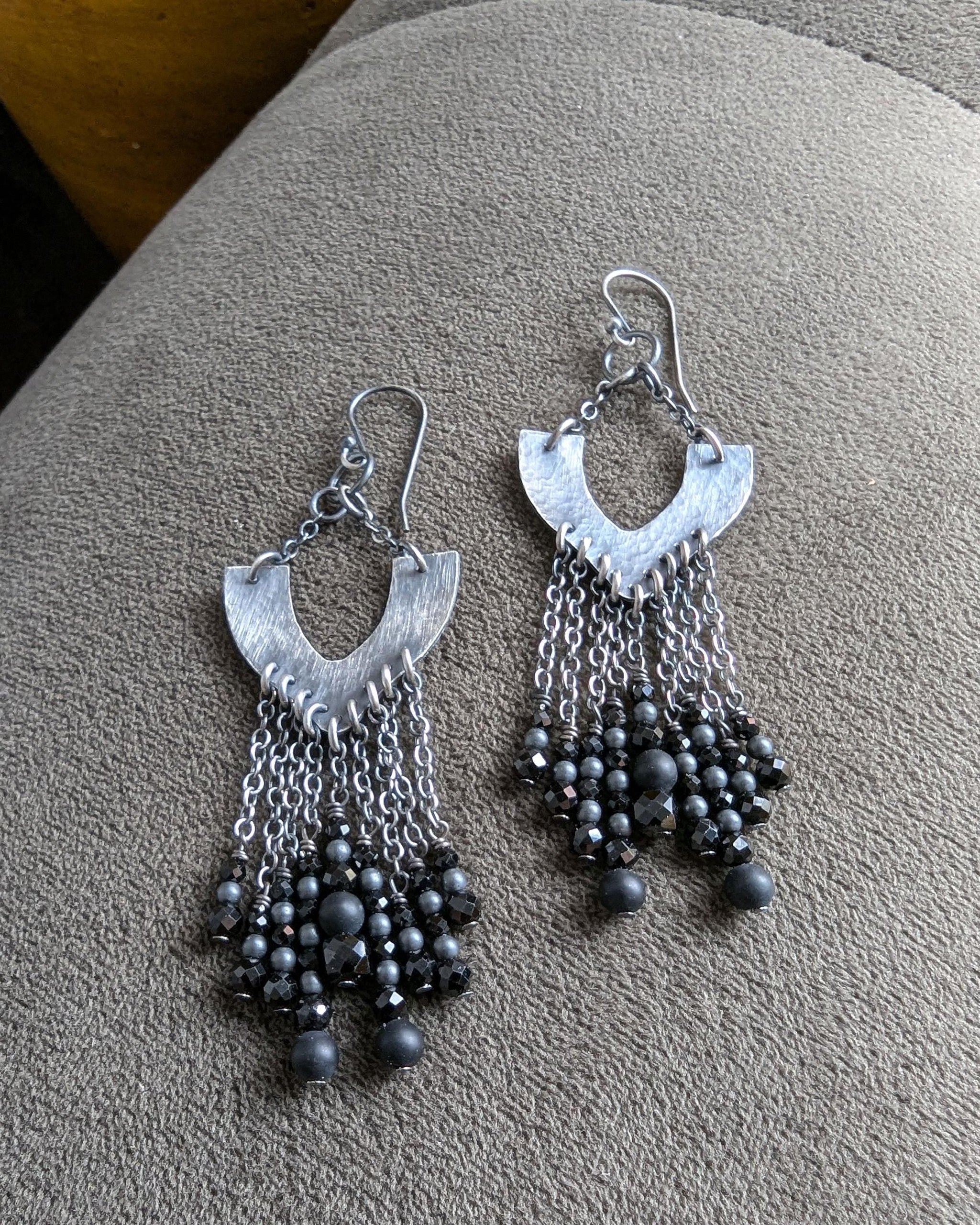 Close-up of hammered oxidized sterling silver chandelier earrings with black beads
