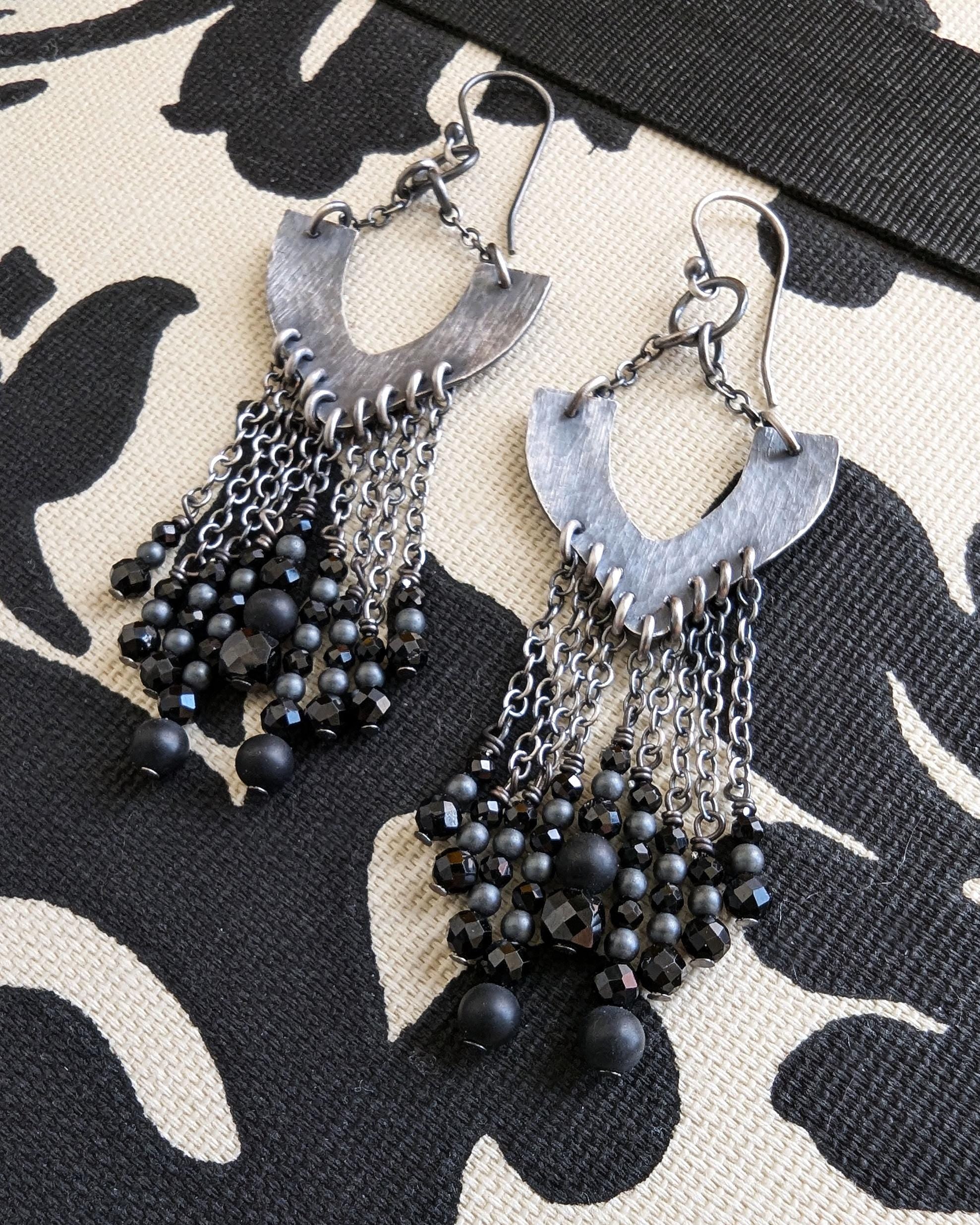 Close photo of black beaded earrings with silver hooks on a patterned fabric background