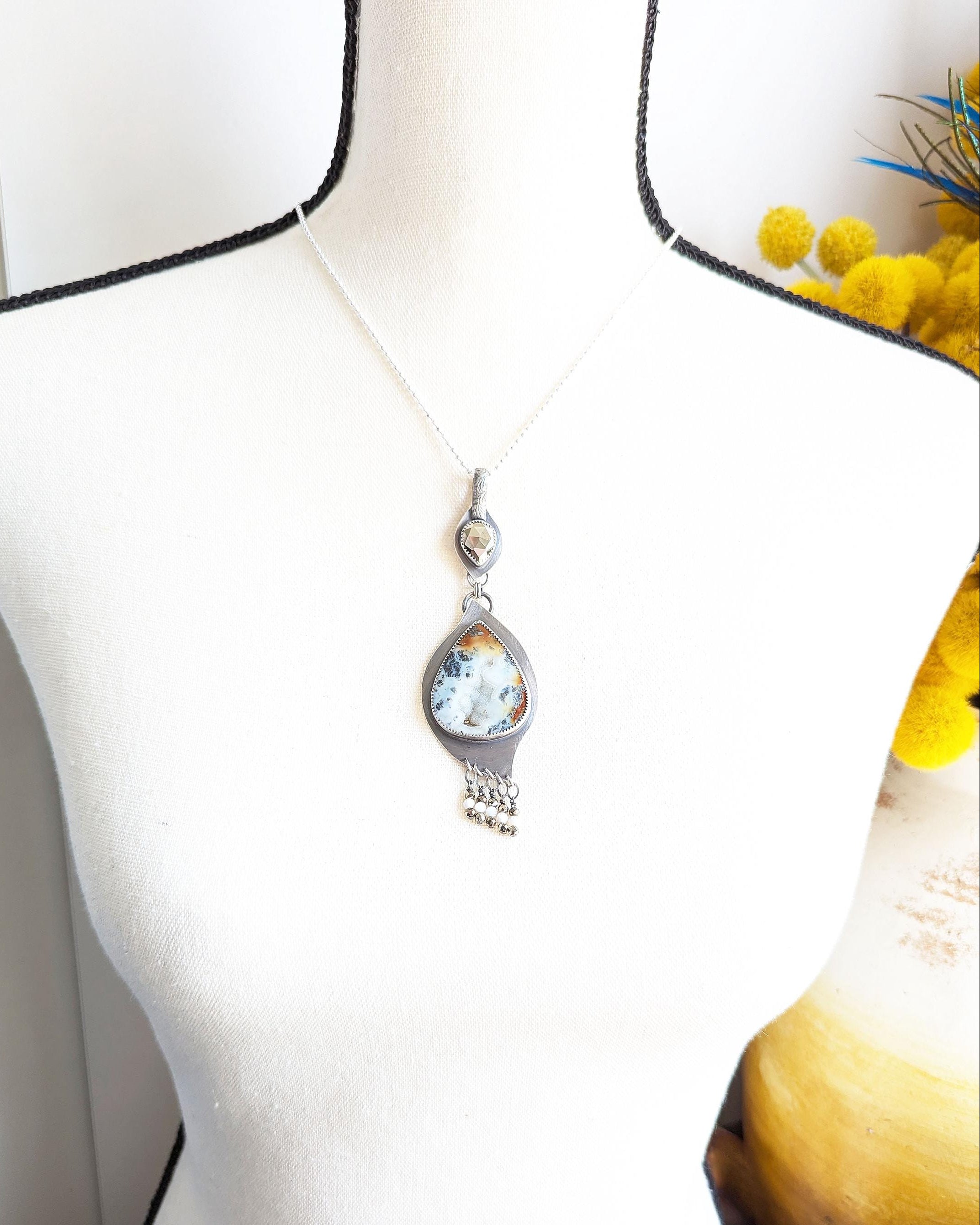 Warm ember-toned agate gemstone set in dark silver on bust for scale