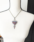 Moody romantic statement pendant with deep red and purple tones on bust for scale