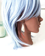 Artisan earrings with natural zebra jasper and coral fringe on mannequin for scale