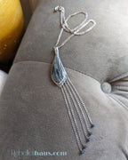 Necklace with a teardrop-shaped pendant and chain on a gray surface