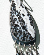 Close up of asymmetrical palm root agate earrings with petal link fringe
