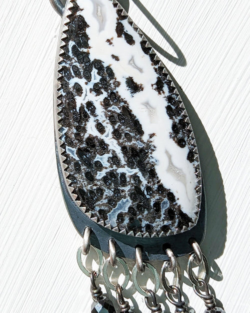 Close up of asymmetrical palm root agate earrings with petal link fringe