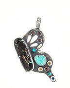 Hand-pierced wing details on sterling silver butterfly pendant in bright white light.

