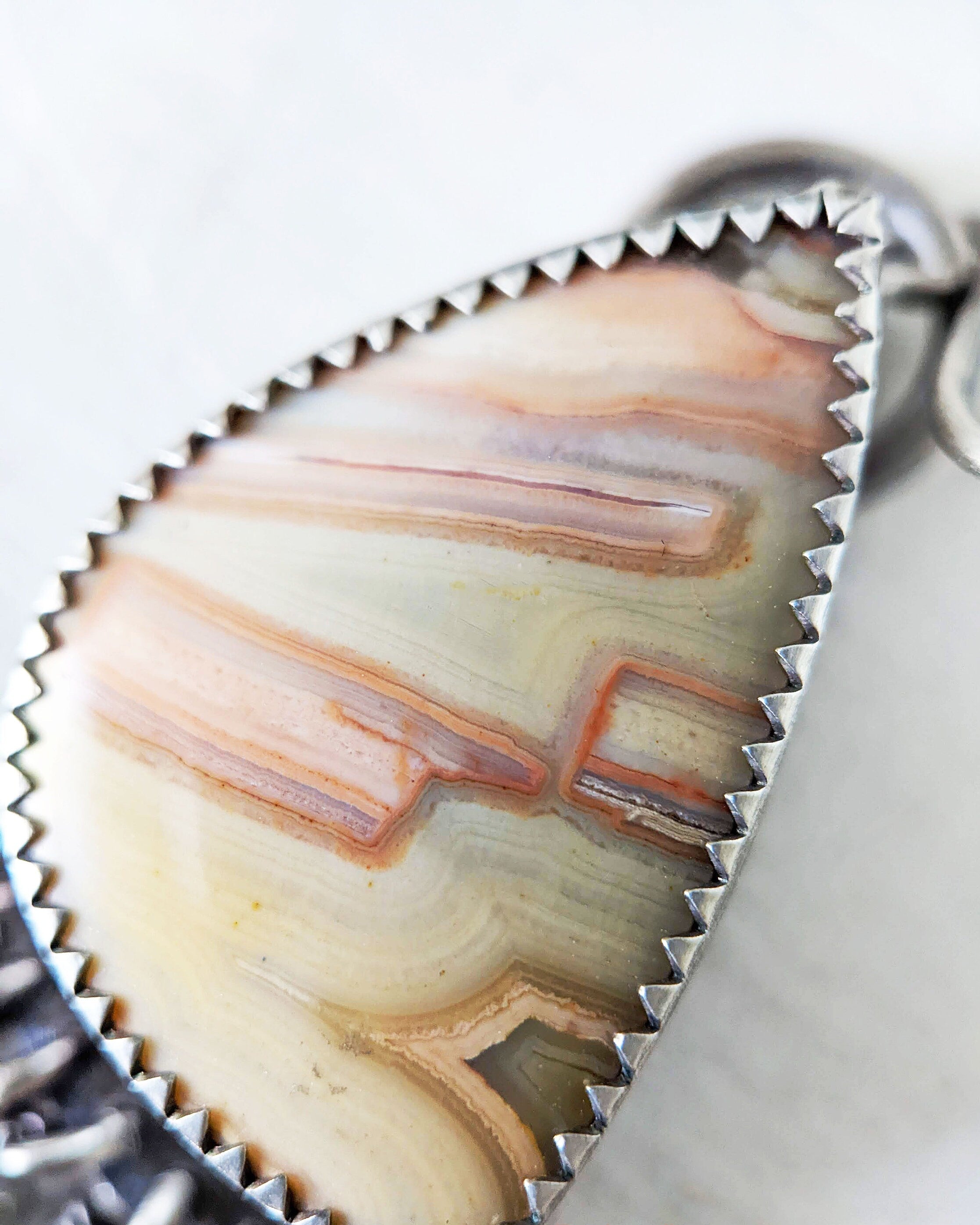 Close up of  the main stone a pink, cream, and peach banded agate