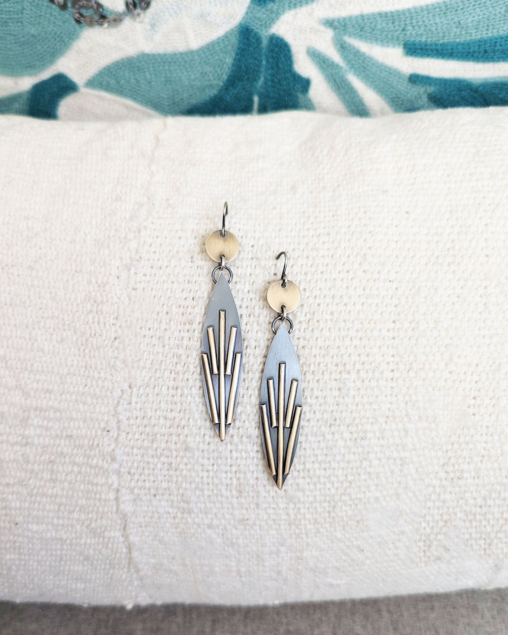 Pair of earrings on a white cushion with a floral-patterned fabric background