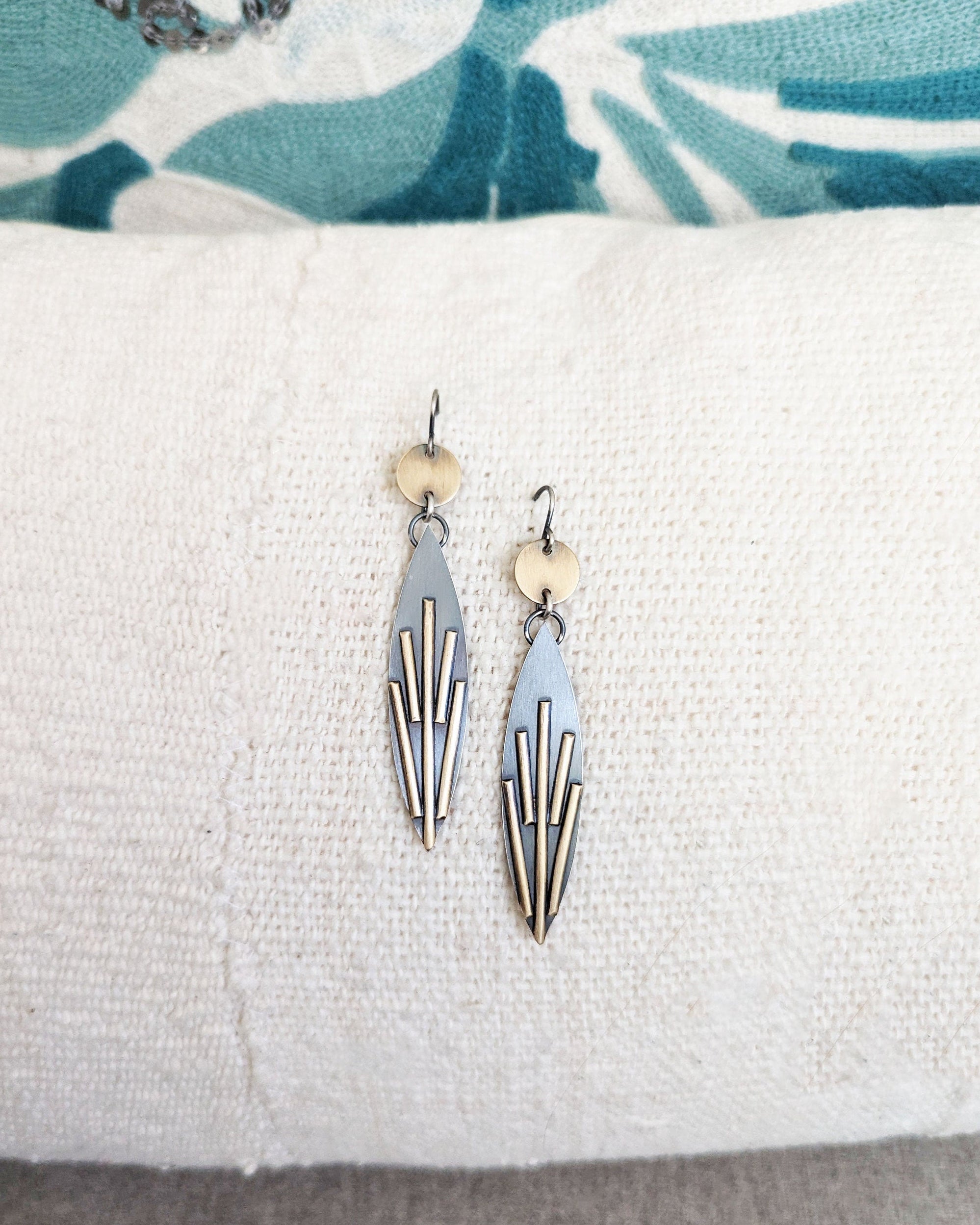 Pair of earrings on a white cushion with a floral-patterned fabric background