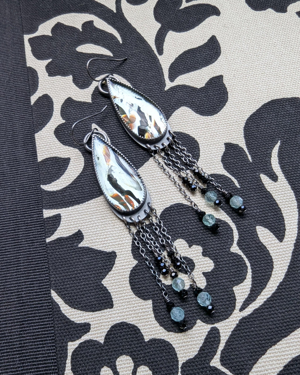 Close-up of reclaimed aqua glass with copper and black accents in silver earrings
