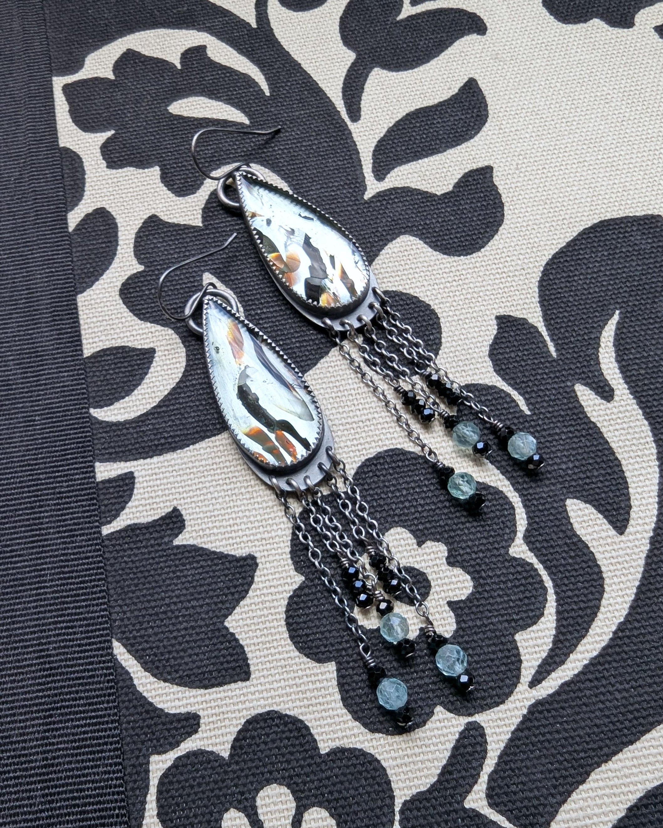 Close-up of reclaimed aqua glass with copper and black accents in silver earrings
