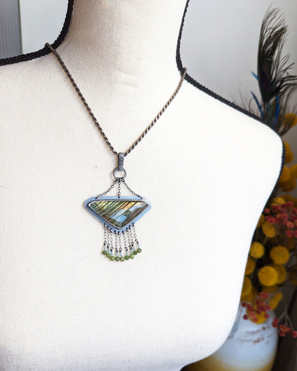 Labradorite pendant worn on chain to show triangular shape and chandelier width on a bust for size
