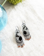 Pair of silver earrings with septarian stones and orange accents on a white surface.