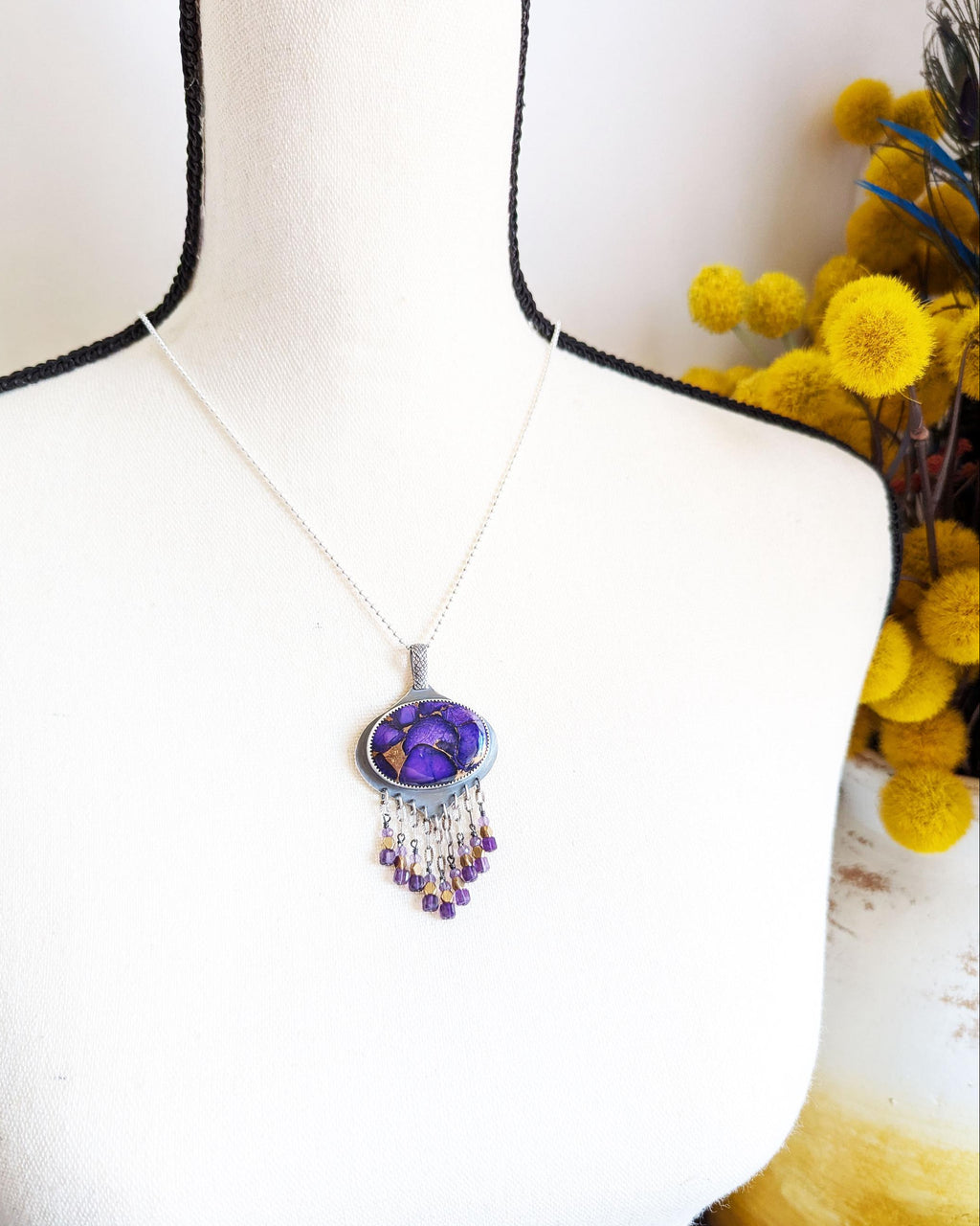 Boho luxe gemstone pendant featuring copper turquoise and amethyst on bust for scale