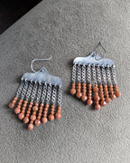 Close up of burnt umber orange goldstone bead drops on sterling silver earrings
