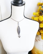 Handcrafted black rutile quartz pendant by Rebellenhaus on bust for scale