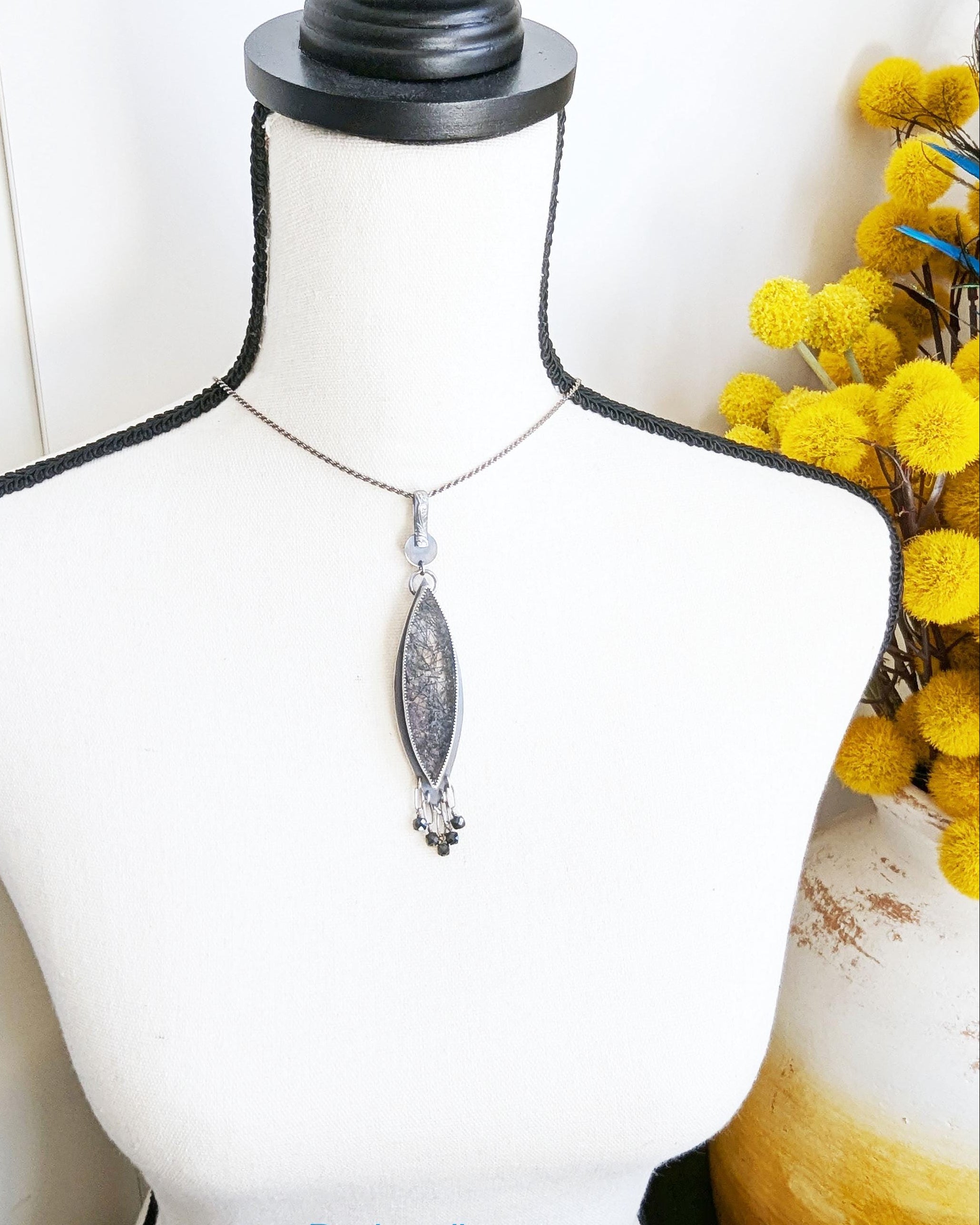 Handcrafted black rutile quartz pendant by Rebellenhaus on bust for scale