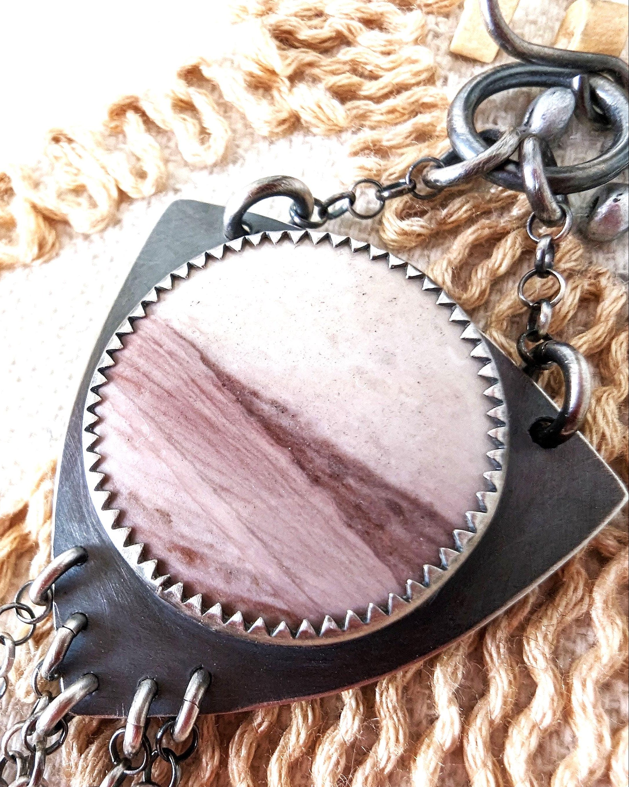 Close up of pink stone and grey metalwork on a textured surface