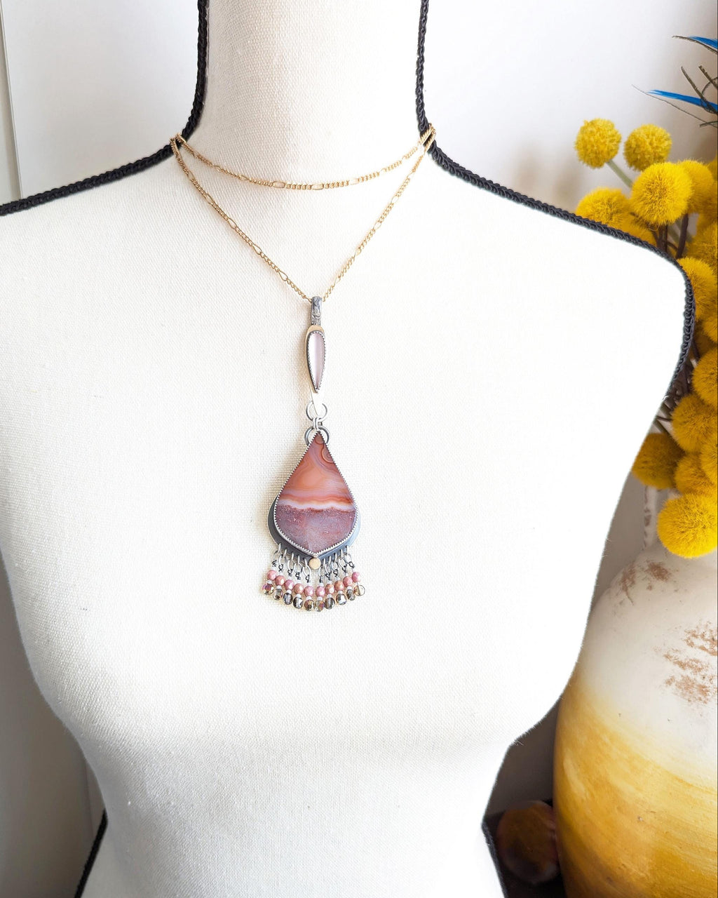 Collector mixed metal pendant featuring pink glass and natural agate on bust for scale