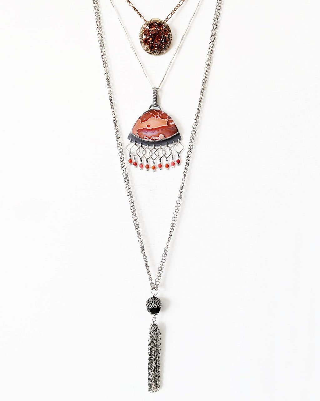 Statement orange agate pendant with square link fringe and coral accents layered with necklaces for styling