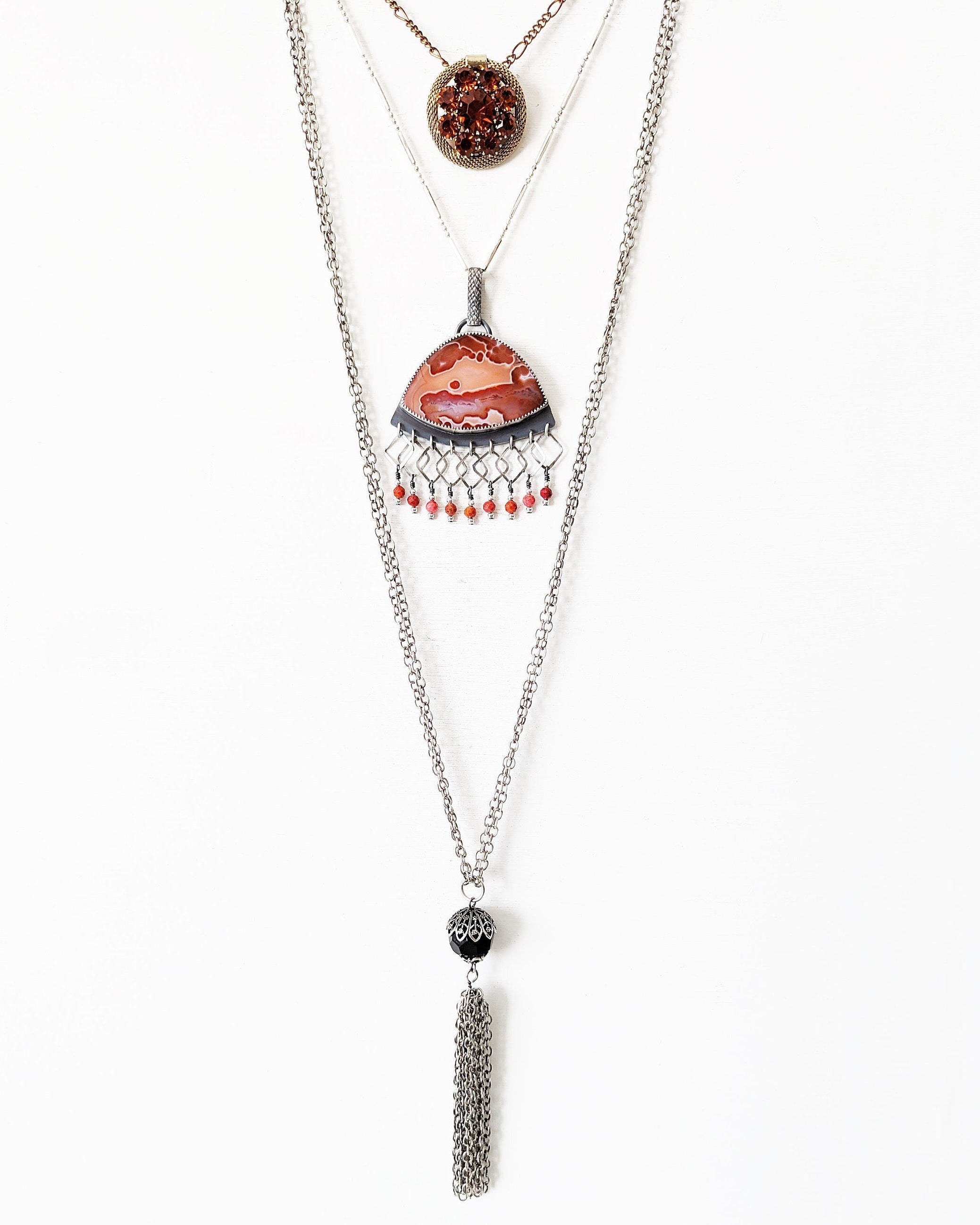 Statement orange agate pendant with square link fringe and coral accents layered with necklaces for styling
