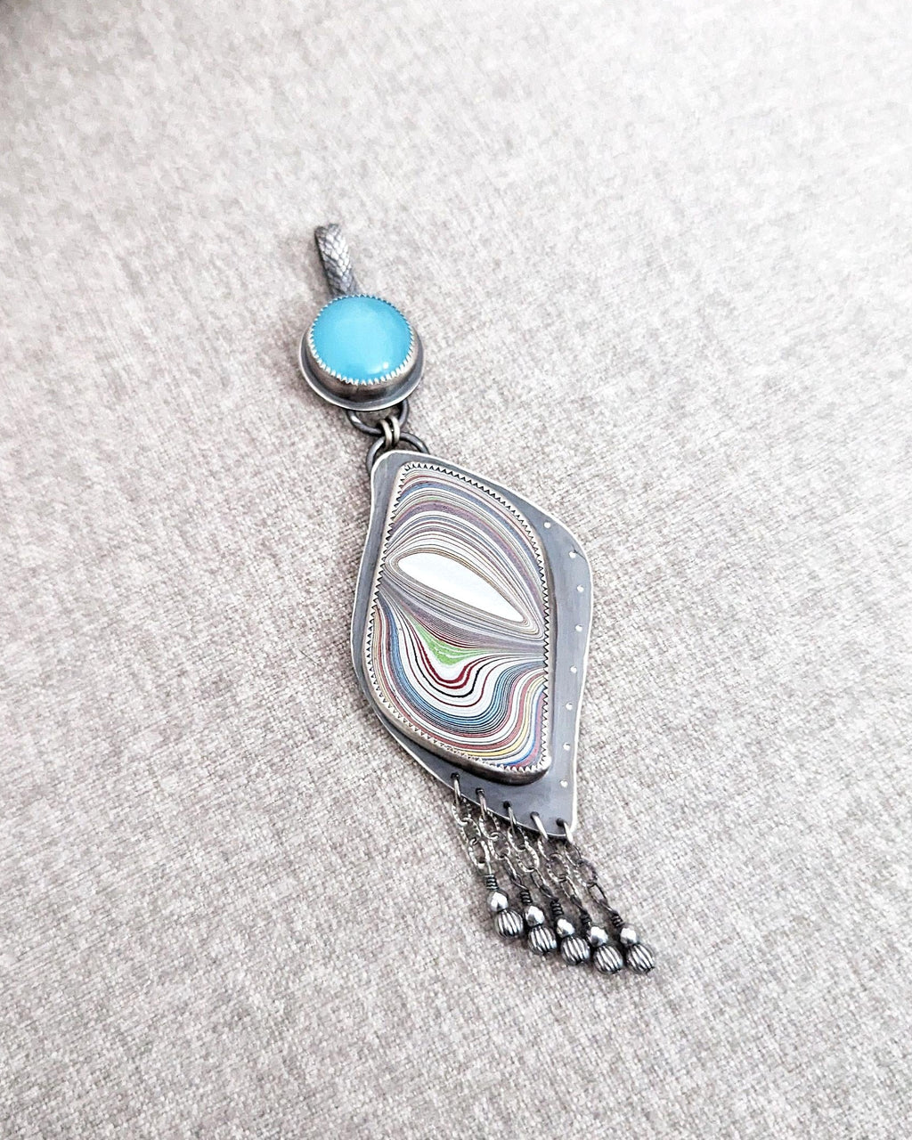 Collector gemstone pendant with layered blue and silver shimmer