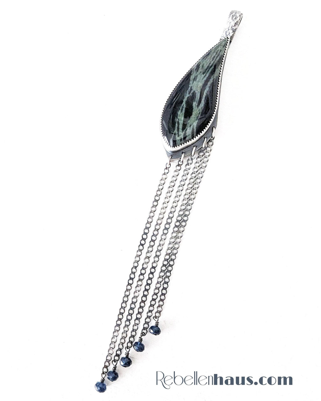 Decorative pendant with chains and a green stone on a white background, featuring the brand 'Rebellenhaus.com'.