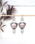 Pair of earrings with pink and mauve gemstones on a white background 