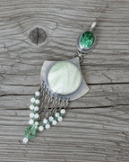 Pendant with green gemstones on a grey wood background