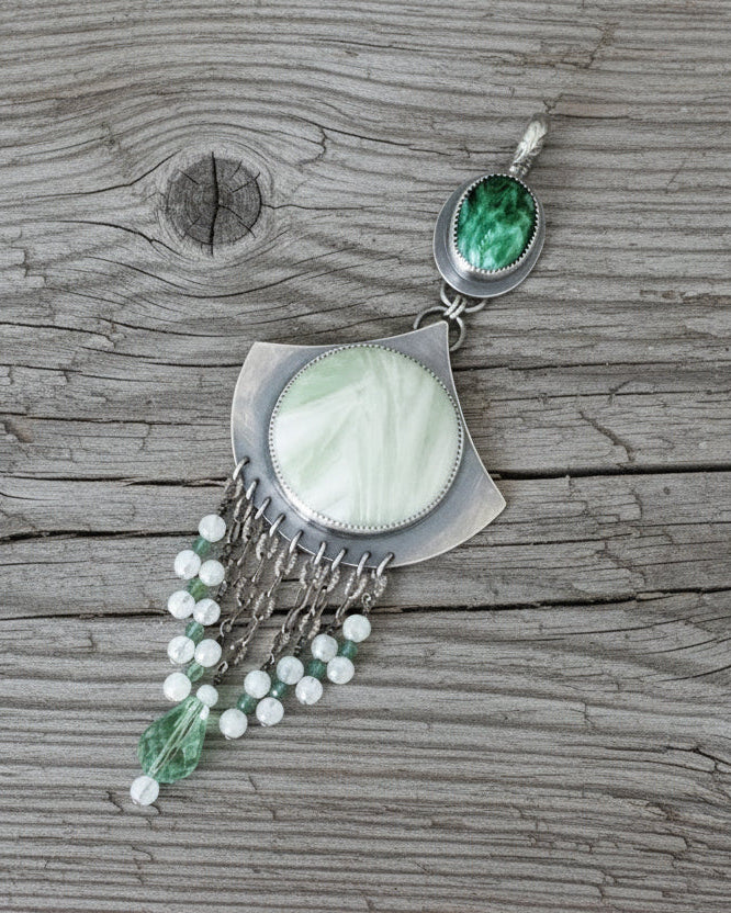 Pendant with green gemstones on a grey wood background