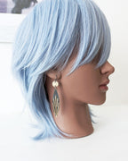 Mannequin head with light blue hair and earrings on a white background.