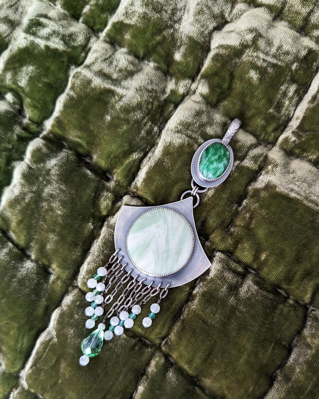 Jewelry with green gemstones and white stones on a textured green surface