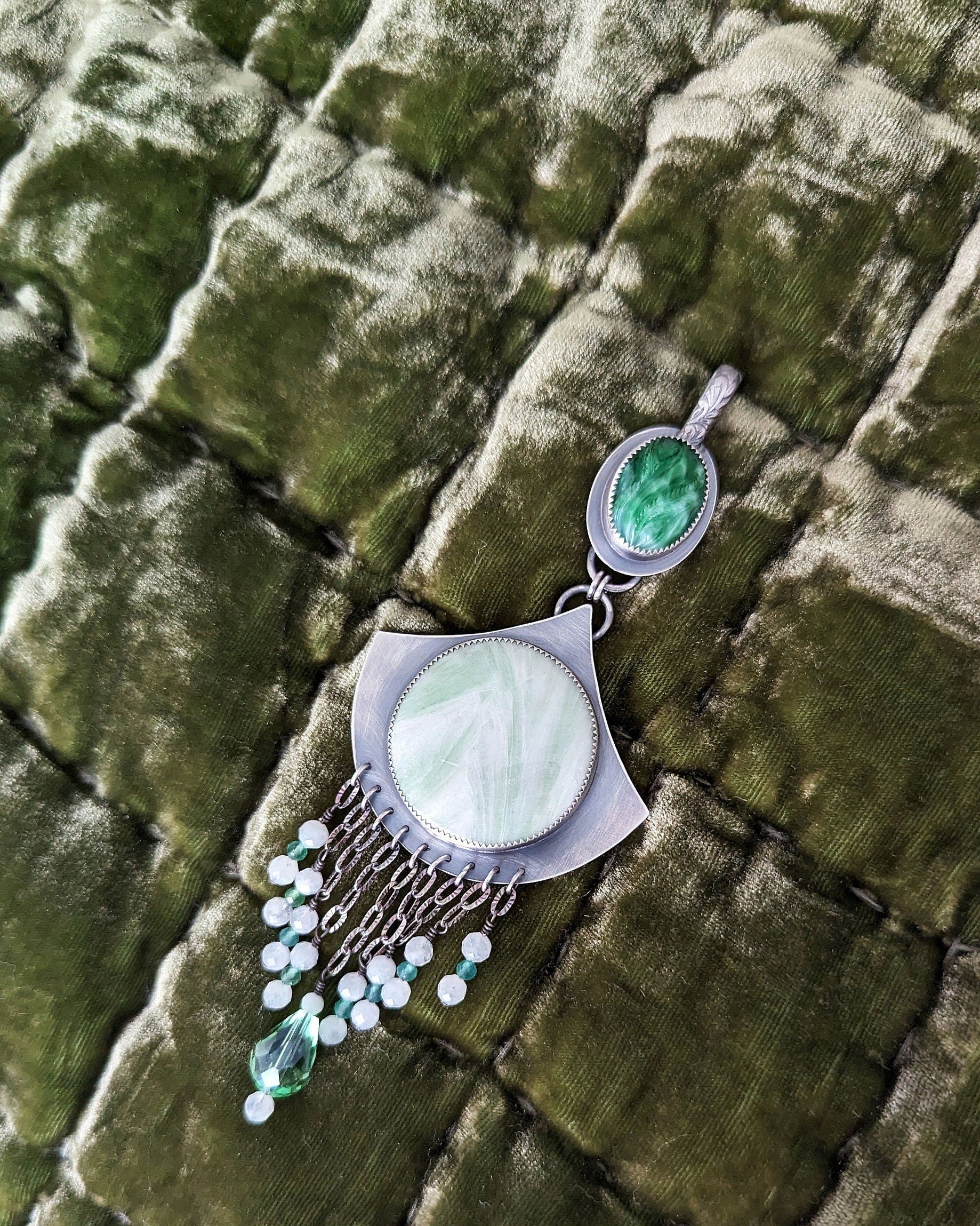 Jewelry with green gemstones and white stones on a textured green surface