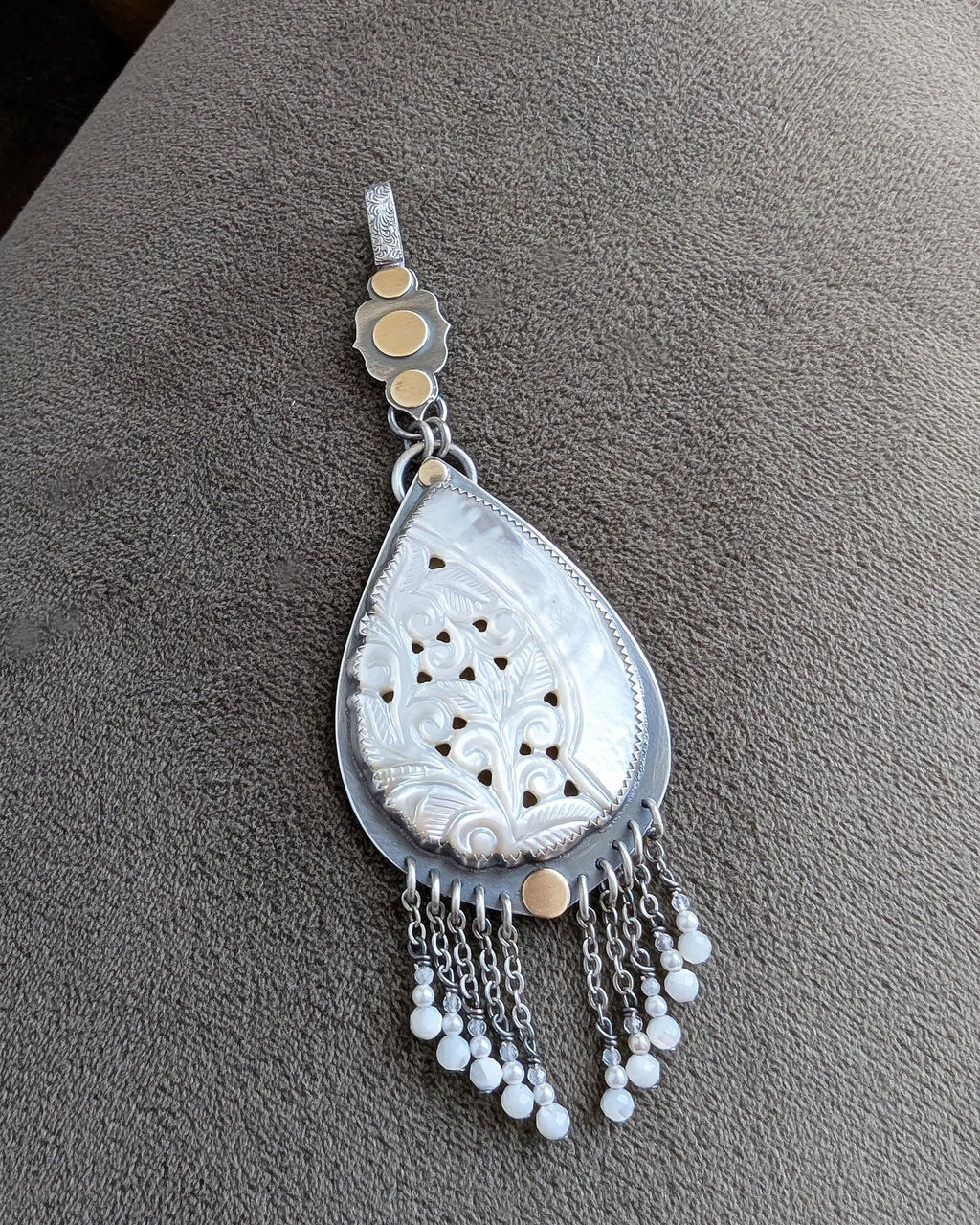 mixed metal pendant with carved mother of pearl and fringe