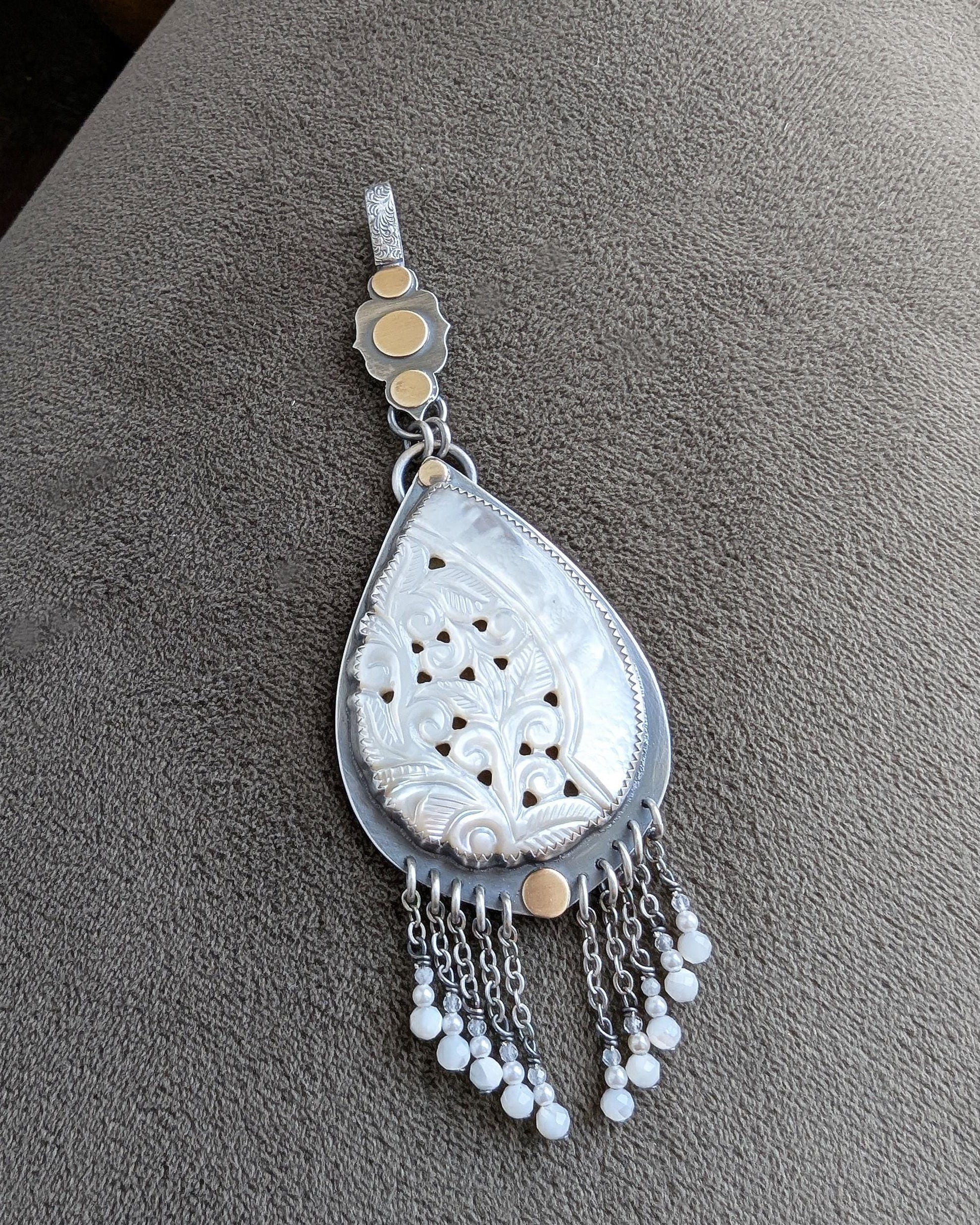 mixed metal pendant with carved mother of pearl and fringe