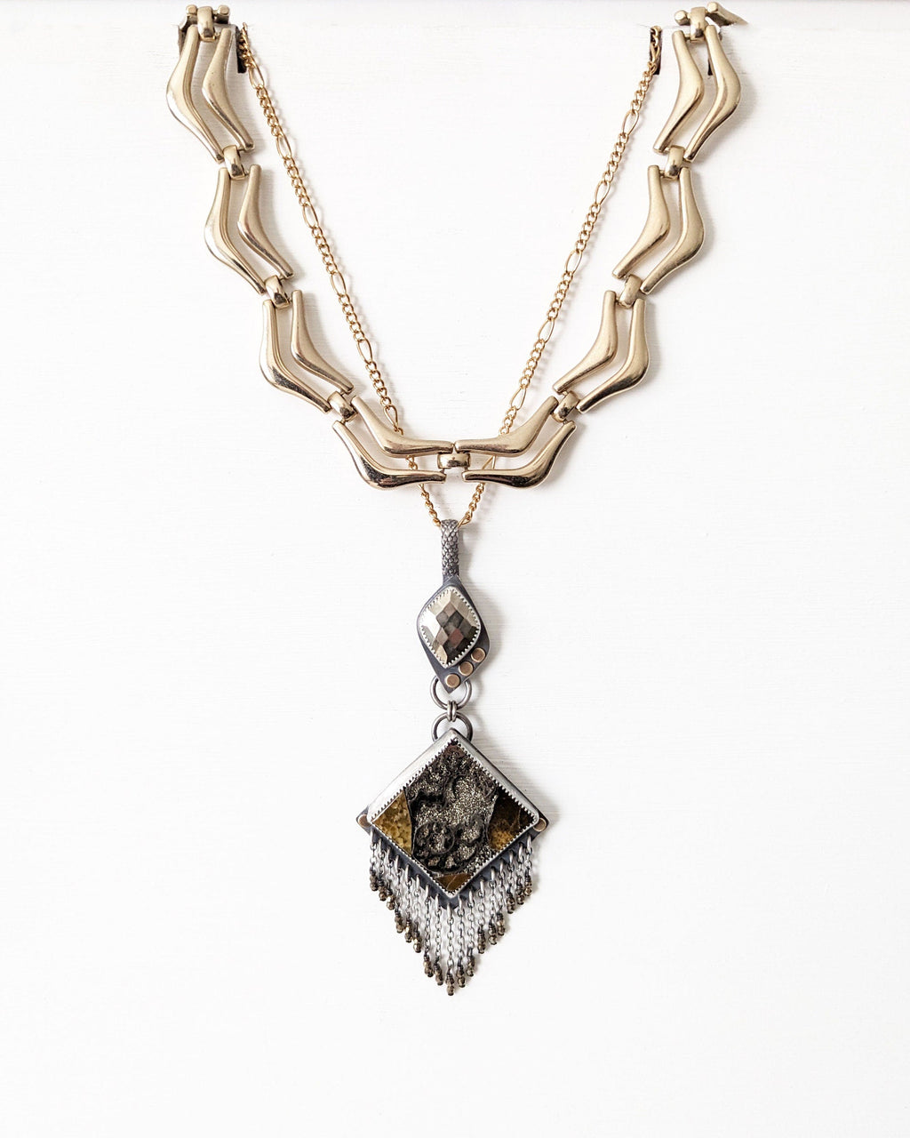 Artisan ammonite and simbircite pendant with pyrite fringe shown hanging with layering necklace for styling