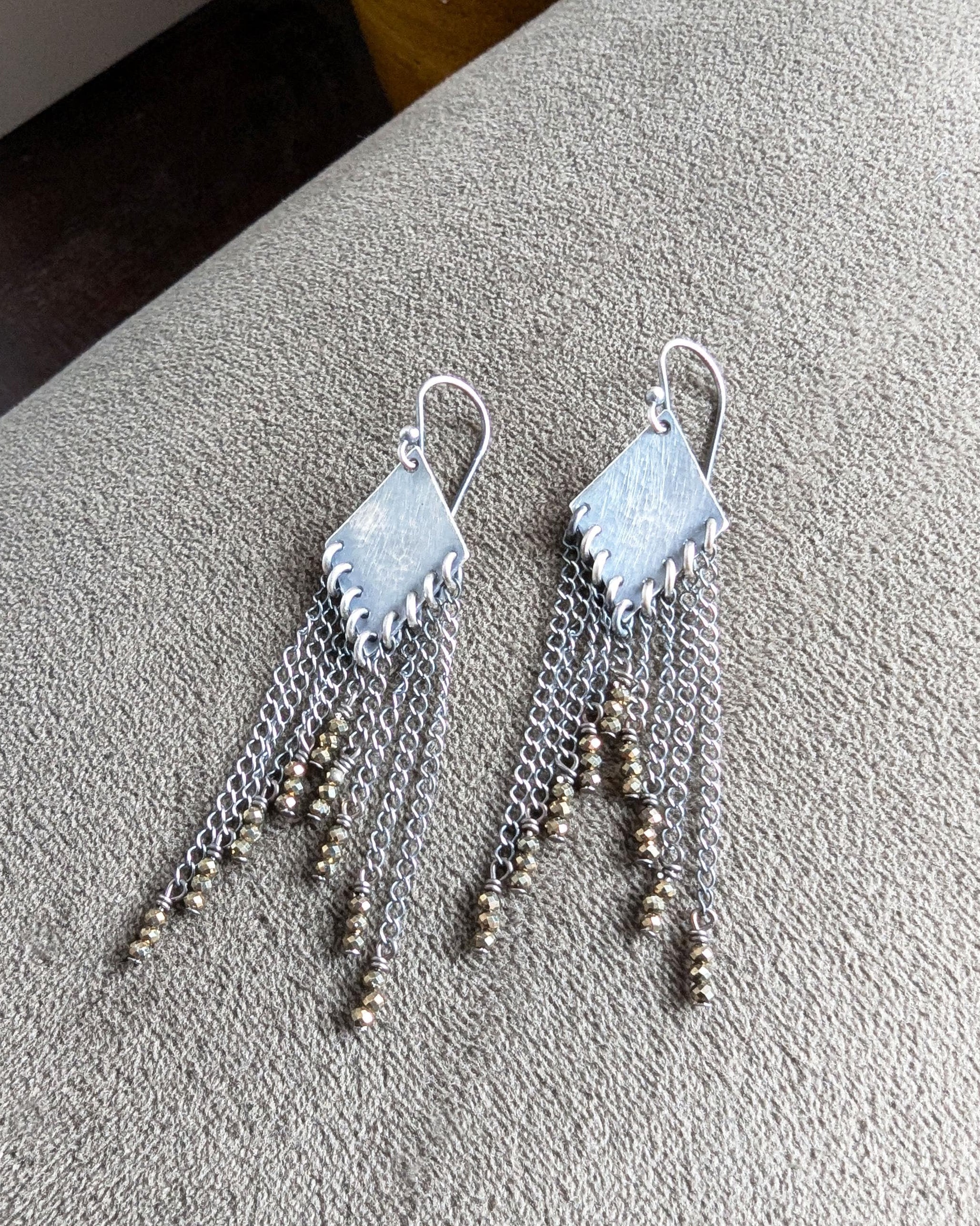 Close up of pyrite fringe earrings with diamond-shaped oxidized sterling silver drops

