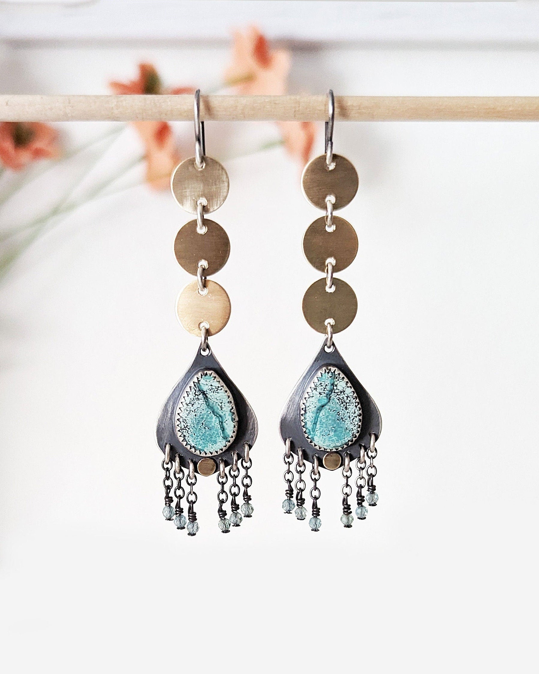 Pair of earrings with turquoise teardrop designs and gold accents on a white background.