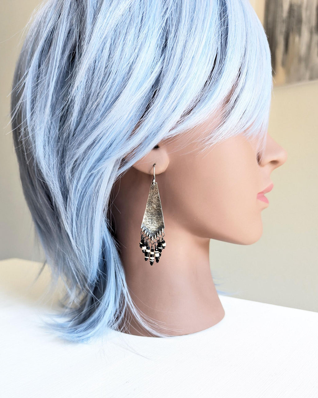 Hand-forged sterling silver arrow dangle earrings on mannequin for scale