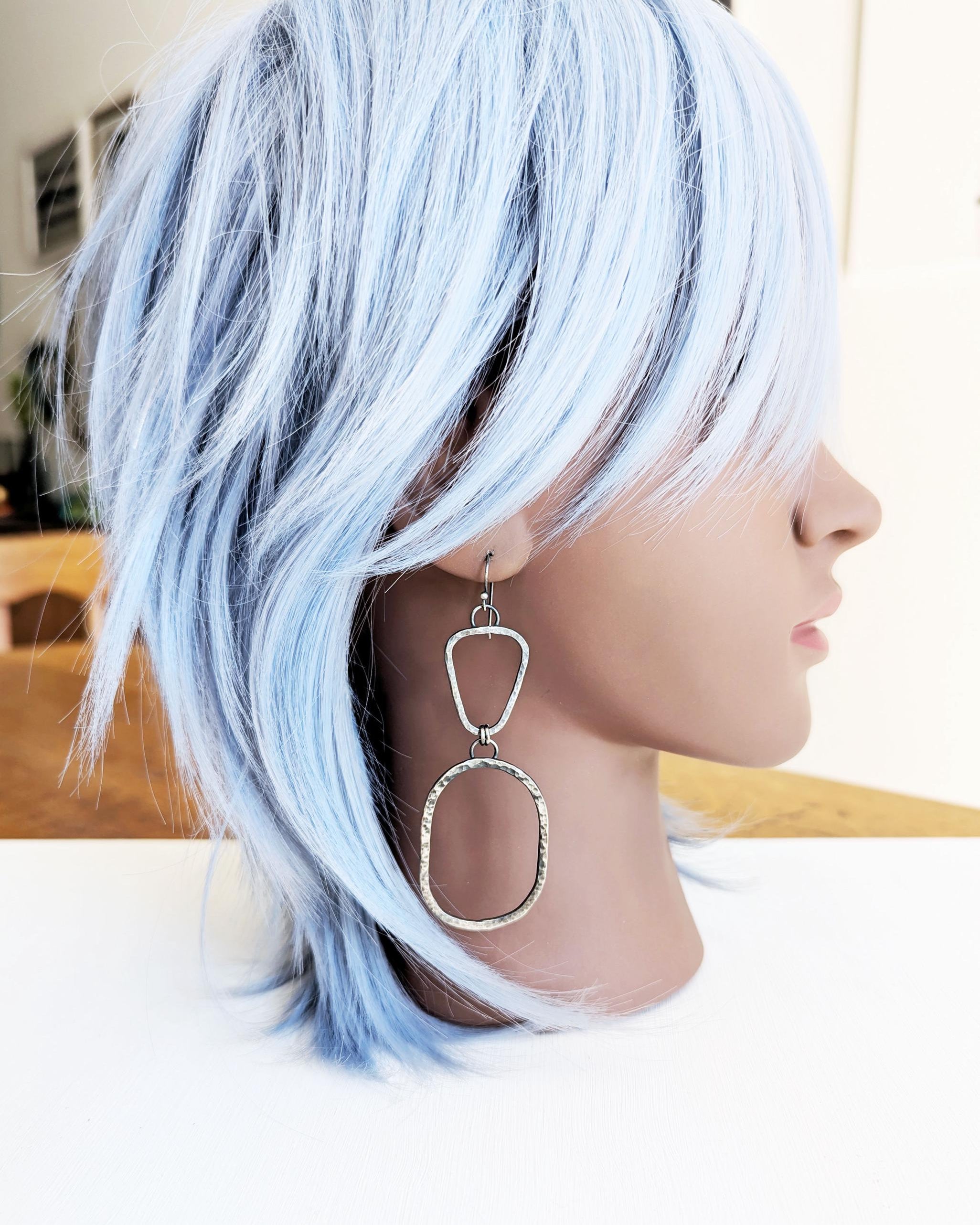 Mannequin with blue hair wearing a large silver 
earring.
