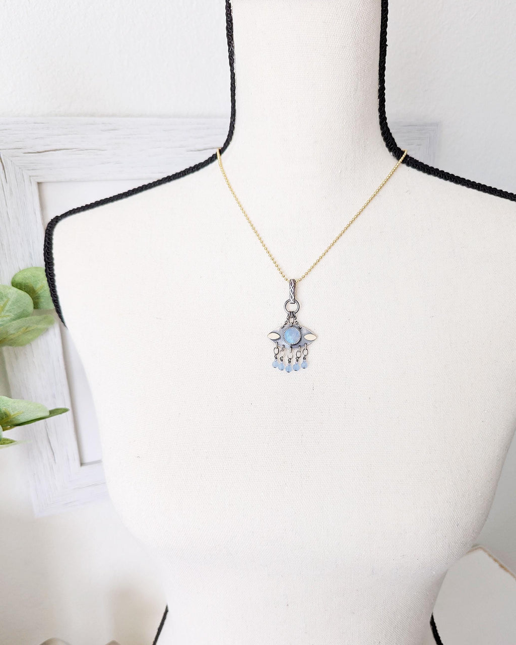 Pale blue crystal and CZ fringe beneath iridescent moonstone on bust for scale