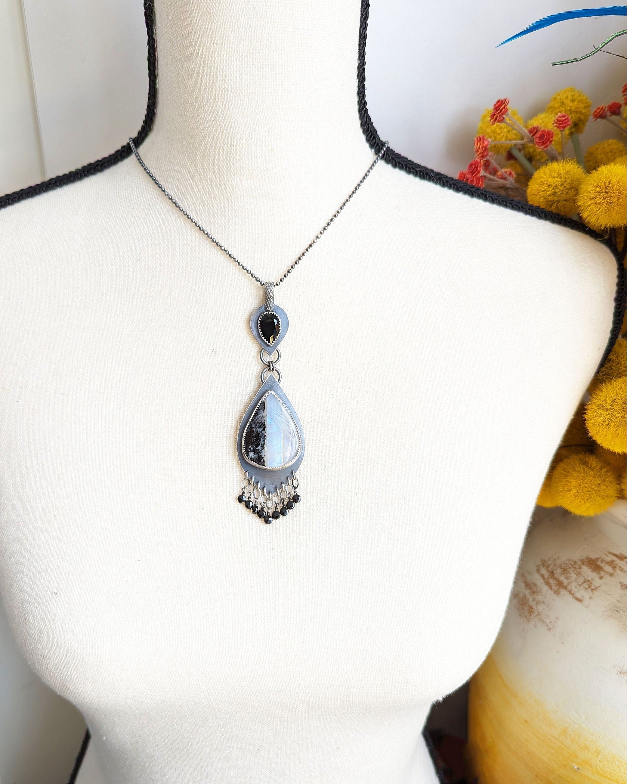 Mystical rainbow moonstone necklace with oxidized silver setting shown on bust for scale